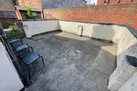 Walled paved rear yard with high brick boundary...