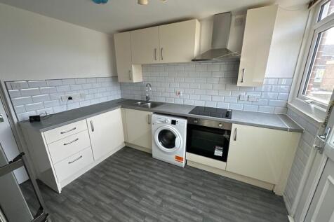 A modern kitchen featuring sleek cream cabinets...