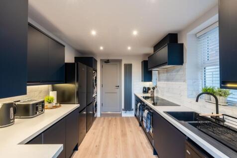 Modern galley kitchen with sleek dark cabinetry...