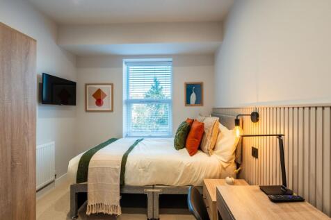 Bright, neatly styled bedroom with a comfortabl...