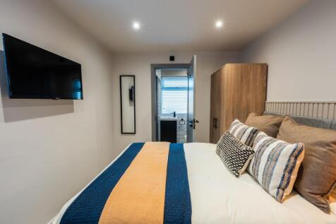 Bright, modern double bedroom with layered bedd...