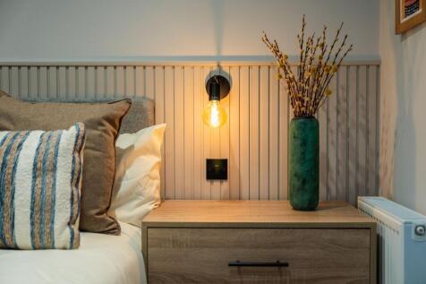 Stylish bedside setup with a warm wall sconce, ...