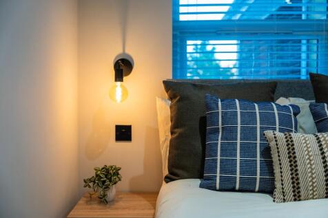 Cozy, stylish bedroom corner with layered cushi...