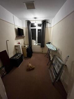 Long, simple single bedroom with a window, radi...