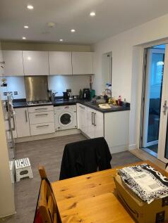 Modern fitted kitchen with white cabinets, blac...