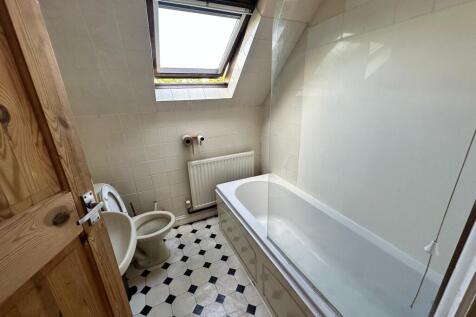 Bright attic bathroom with a skylight, bathtub ...
