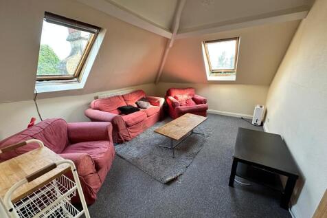 Bright attic living room with sloped ceilings a...