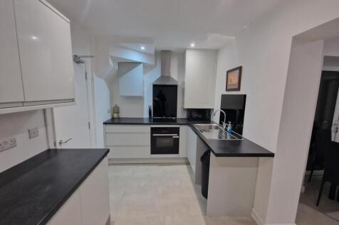 Modern white kitchen with black worktops, integ...