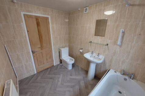 Bright, tiled bathroom with a modern white bath...