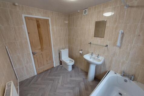 Bright, fully tiled bathroom with a bath, pedes...