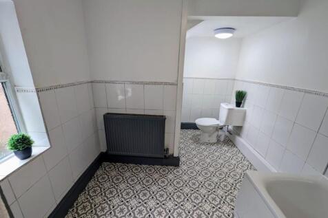 Bright, tiled bathroom with patterned floor til...