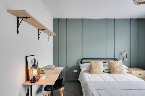 Bright, modern double bedroom with a soft green...