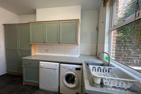 Bright, tidy kitchen with sage-green fitted cup...