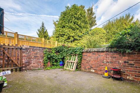 Private paved rear courtyard with high brick wa...