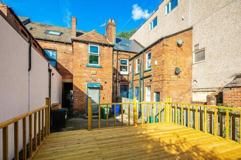 Sunny raised wooden deck overlooking a brick-bu...