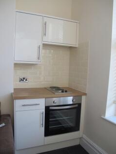 Modern compact kitchenette with white cabinetry...