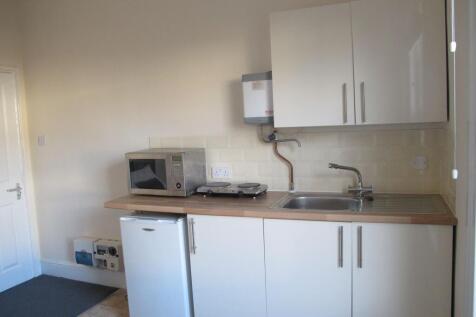 Compact modern kitchenette with white cabinets,...
