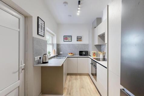 A modern, well-lit kitchen with white cabinets ...