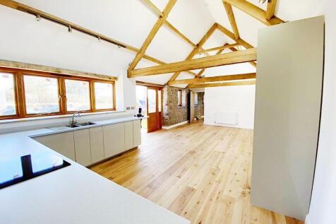 Bright, open-plan living space with exposed tim...