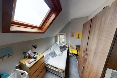 A well-lit bedroom with a large window bringing...