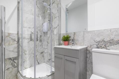 Bright modern bathroom with a corner glass show...