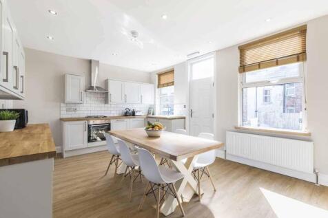 Bright, modern kitchen with white cabinetry, wo...