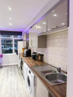 Bright modern kitchen with long wooden worktop,...