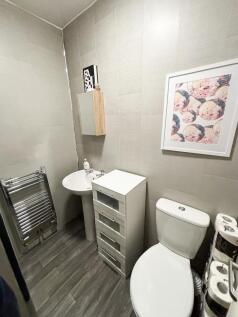 Modern tiled bathroom with a white toilet, pede...