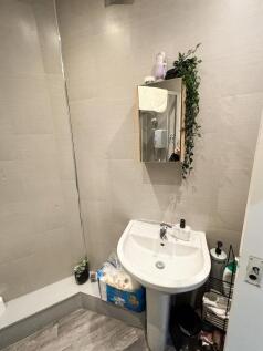 Bright, modern bathroom with tiled walls, a ped...