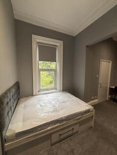 A well-lit double bedroom featuring a comfortab...