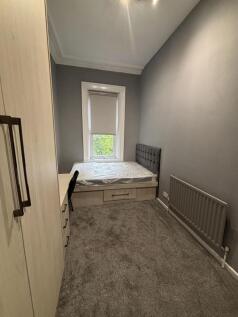 A cozy student bedroom featuring a single bed b...