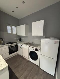 A modern kitchen area featuring white cabinetry...