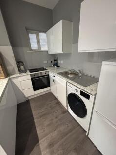 A modern, compact kitchen area featuring white ...