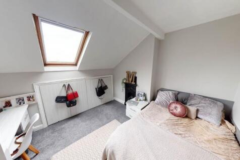 A bright, spacious master bedroom with a cozy b...