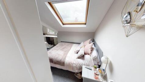 A cozy single bedroom with a neatly made bed, s...