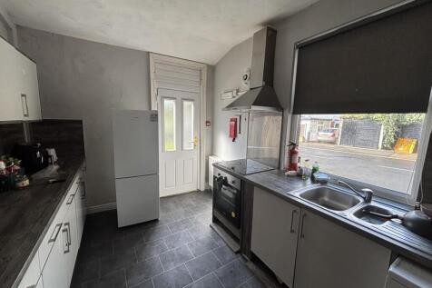 Bright, modern galley kitchen with white cabine...