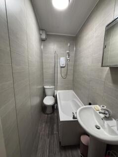 Compact, modern bathroom with tiled walls, a wh...