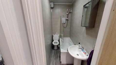 Compact, modern bathroom with a bathtub/shower ...