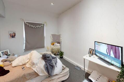 A cozy bedroom with a bed, some clothes on it, ...