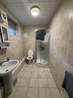 Well-maintained bathroom featuring a shower enc...