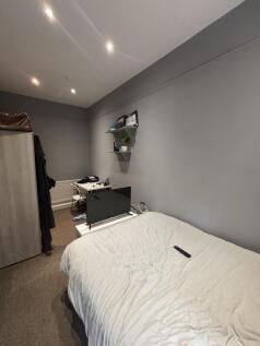 A cozy bedroom with a neatly made bed, subtle g...