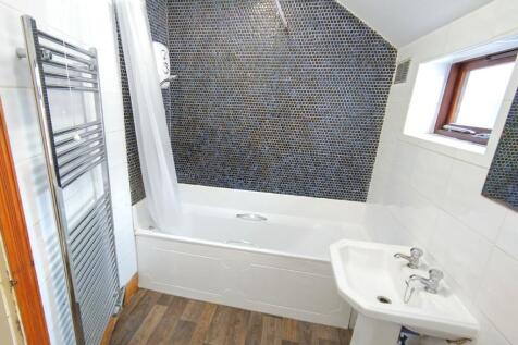 Bright, modern bathroom with a white bathtub an...