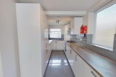Bright modern galley kitchen with glossy white ...