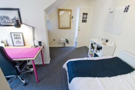 Bright, neatly furnished bedroom with a study d...