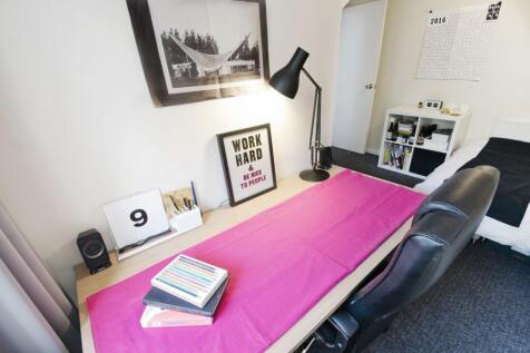 Bright, neatly arranged single bedroom with a l...