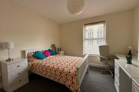Bright, neatly furnished bedroom with a double ...