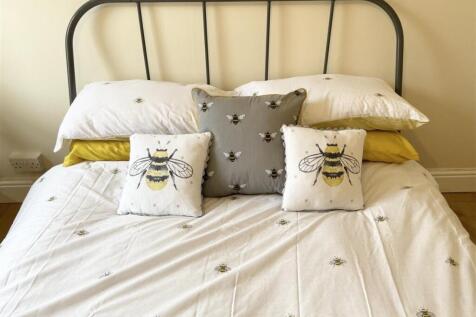 Bright, neatly made double bed with a stylish m...