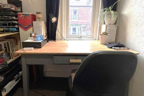 Well-lit workspace by a window with a wooden de...