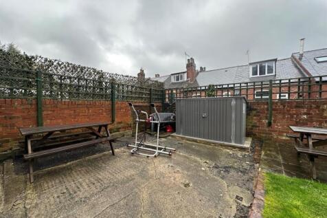 Enclosed paved garden area with brick walls, be...