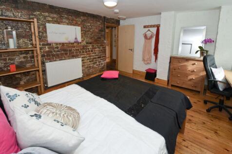 Bright, stylish bedroom with exposed brick feat...